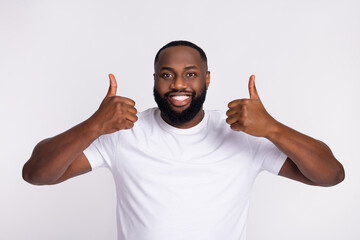 Wall Mural - Photo of confident cute man wear casual t-shirt smiling showing thumbs up isolated white color background