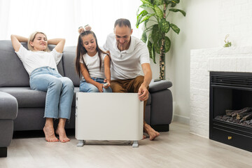 Wall Mural - Electric heater at home. Young family warms near a heating radiator.