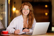 Young beautiful smiling student woman working with laptop looking into camera