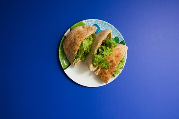 Top view of a plate with toasted pitas with lettuce on the blue background