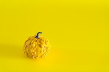 Yellow Decorative Pumpkin Against The Yellow Background With Copy Space