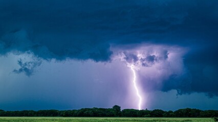 Wall Mural - Beautiful shot of purple lightning striking on a field