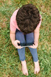 © ADDICTIVE STOCK - Boy using smartphone on park lawn