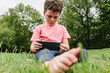 © ADDICTIVE STOCK - Barefoot boy browsing cellphone on lawn