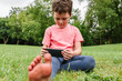 © ADDICTIVE STOCK - Barefoot boy browsing cellphone on lawn