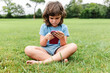 © ADDICTIVE STOCK - Girl using smartphone on park lawn