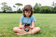© ADDICTIVE STOCK - Happy girl using smartphone on park lawn