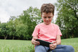 © ADDICTIVE STOCK - Happy boy using smartphone on park lawn