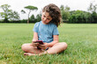 © ADDICTIVE STOCK - Girl using smartphone on park lawn