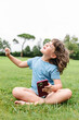 © ADDICTIVE STOCK - Cheerful girl using smartphone on park lawn