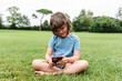 © ADDICTIVE STOCK - Cheerful girl using smartphone on park lawn