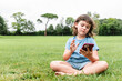 © ADDICTIVE STOCK - Unemotional girl using smartphone on park lawn