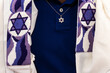 Detail of a Jewish man wearing a tallit or prayer shawl decorated with Jewish stars and a necklace with a gold Magen David pendant.