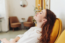 Young Woman Relaxing In Armchair With Closed Eyes