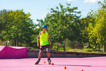 Wall Mural - Child in blue helmet skate fast on rollerblades around cones