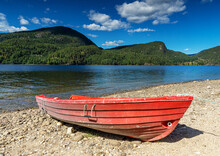 Red Boat On The Pebble Beach At The Lake In Norway