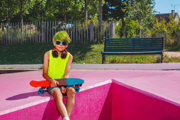 Wall Mural - Child with green hair and skateboard sit on ramp, low angle view