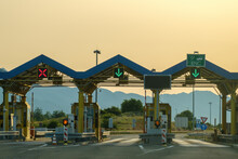 Paid Expressway Checkpoint Tollgate Shows Right Direction On Highway. Expressway Green Signs Allow Driving Against Hills At Back Sunset
