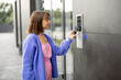 © rh2010 - Young stylish woman getting access to the building by attaching smartphone to intercom. Concept of modern security technologies for access and smart home