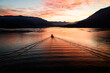 © And7w - Ferry boat transport cars and passengers through the Como Lake during the sunset. Colorful Sunset sky and cloud. Travel, quiet and freedom concept.