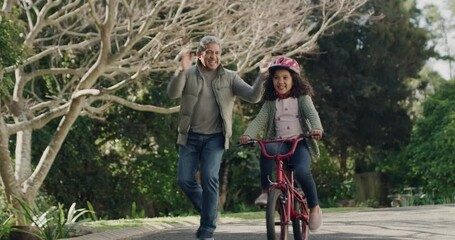 Poster - Grandfather teaching child to cycle on her first bike ride, happy child outdoors learning on a bicycle in a street. Smiling, clapping and proud grandpa having a bonding moment with his grandchild.