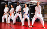 Adults in kimono trying new martial moves at karate class