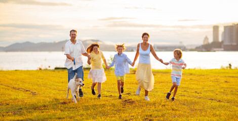 Wall Mural - Family with kids running outdoor at sunset.