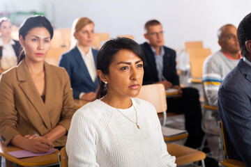 Wall Mural - Portrait of focused Latina attending business conference, listening with interest to speaker