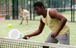 African american man and his female partner playing paddle tennis on the padel court