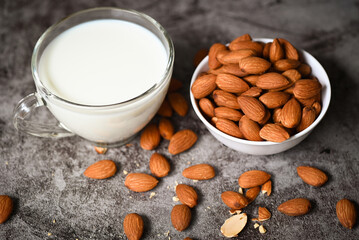 Wall Mural - Almond milk and Almond nuts on white bowl with on dark background, Delicious sweet almonds on the table, roasted almond nut for healthy food and snack