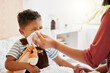 © Kay Abrahams/peopleimages.com - Flu, sick or cold child with parent sneezing, blowing and wiping runny nose while ill with covid virus, sinus and allergy symptoms in bed at home. Mother caring for stuffy and congested little son
