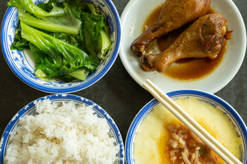 top view fast food of two chicken thighs and steamed eggs and vegetable and bowl of rice horizontal composition