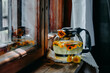 Calendula tea in a glass teapot on a wooden windowsill