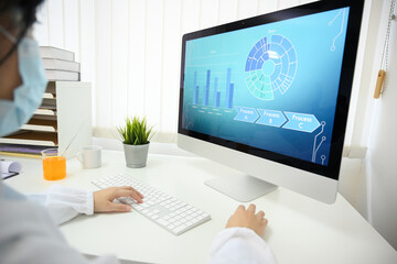 A male scientist working at his office desk looking at his desktop computer.