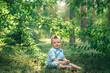© Antonina Trushina - baby, toddler, child sitting in the park under a bush or tree in the rays of the setting sun and smiling