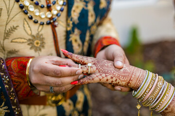 Indian couple's exchanging wedding rings hands close up