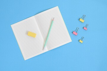 Wall Mural - open notebook with office supplies on blue background