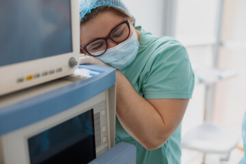 Wall Mural - Tired nurse after difficult surgery near medical equipment in operating room