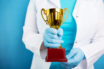 Wall Mural - award cup in doctor's hands on blue background