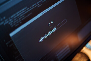 cybercrime, hacking and technology concept - close up of computer monitor with progress loading bar on screen in dark room