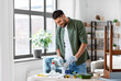 © Syda Productions - repair, diy and home improvement concept - happy smiling man in protective gloves opening can with grey color paint for painting old wooden table