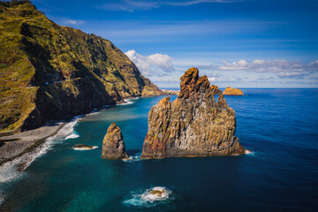 Wall Mural - View of the Ilheus da Ribeira da Janela rock islets under a clear blue sky. The rocks form a famous landmark on the northern shore of the island of Madeira, Portugal. Aerial drone shot, october 2021