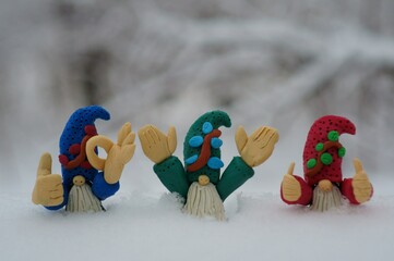 Wall Mural - Three little plasticine gnomes celebrate the new year. Christmas toys and decorations on the background of snow.