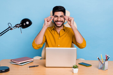 Wall Mural - Portrait of cheerful clever agent man sit chair arms touch glasses use netbook workplace isolated on blue color background