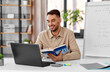 © Syda Productions - distant education, school and remote job concept - happy smiling male math teacher with laptop computer, book and flip chart having online class or video call at home office