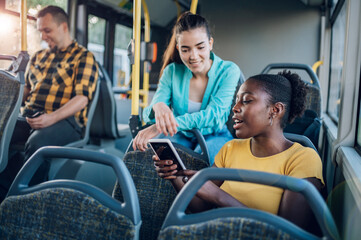 Poster - Multiracial group of friends talking while riding in a bus and using a smartphone