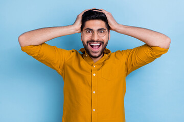 Poster - Photo of speechless staring crazy man wear yellow shirt hold hands on head unbelievable unexpected sale isolated on blue color background