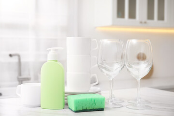 Canvas Print - Clean glasses, cups and cleaning product on table in stylish kitchen