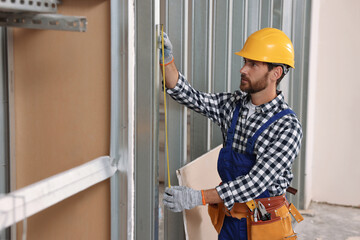 Poster - Professional builder in uniform working with measuring tape indoors