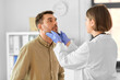 © Syda Productions - medicine, healthcare and people concept - female doctor checking lymph nodes of man patient at hospital